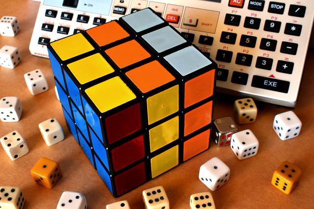 Cubo de Rubik junto a teclados y dados